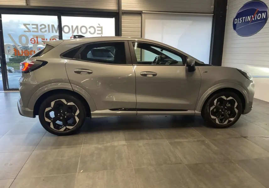 Vue de profil côté gauche d'un Ford Puma gris clair avec jantes alliage noires et détails noirs sur les bas de caisse.