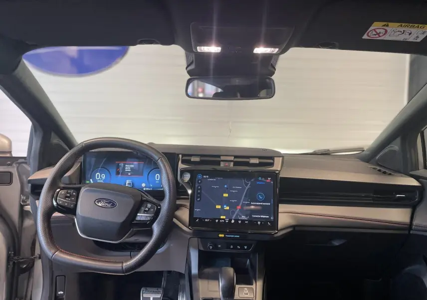 Vue intérieure frontale du tableau de bord du Ford Puma gris clair, avec écran tactile central et volant multifonction.
