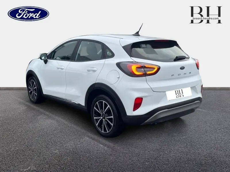 Vue 3/4 arrière droite du Ford Puma blanc Glacier 2020 avec feux arrière LED allumés et jantes alliage noires.