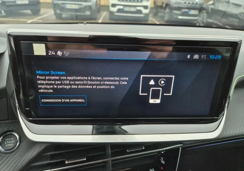 Écran tactile central allumé dans l’habitacle d’une Peugeot 208 gris, vue rapprochée du tableau de bord.