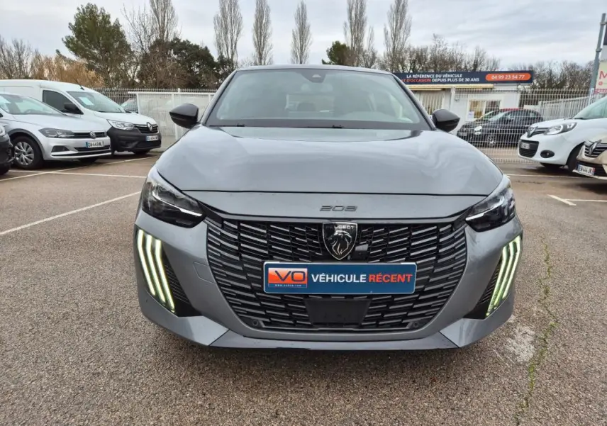 Vue avant d'une Peugeot 208 gris métallisé avec calandre noire et feux diurnes LED verticaux allumés.