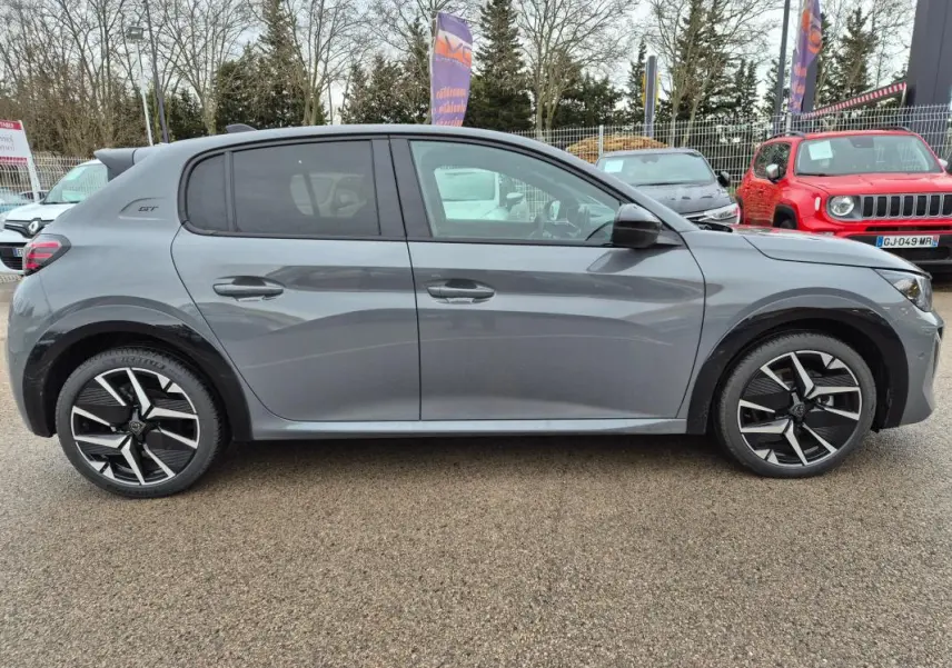 Profil côté droit d'une Peugeot 208 Hybrid 110 e-DCS6 GT gris avec jantes alliage 17 pouces et badge GT visible à l'arrière.