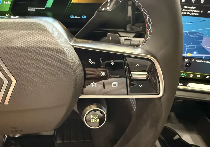 Gros plan sur le volant côté droit du Renault Austral gris Schiste, avec commandes intégrées et bouton Multi-Sense lumineux.