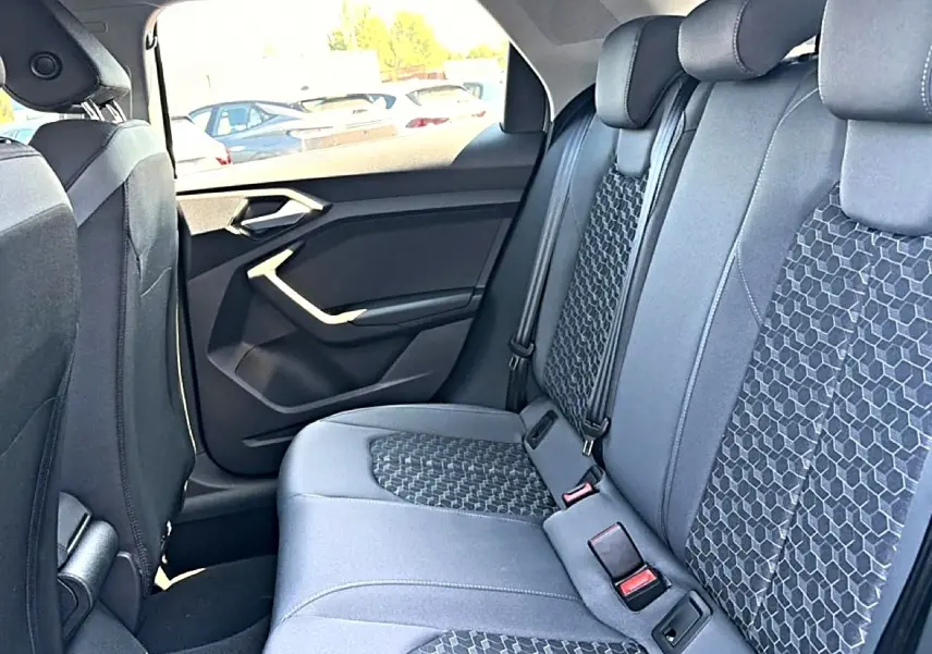 Vue intérieure arrière côté droit de l'Audi A1 Sportback 2026, sièges tissu gris avec motifs hexagonaux.