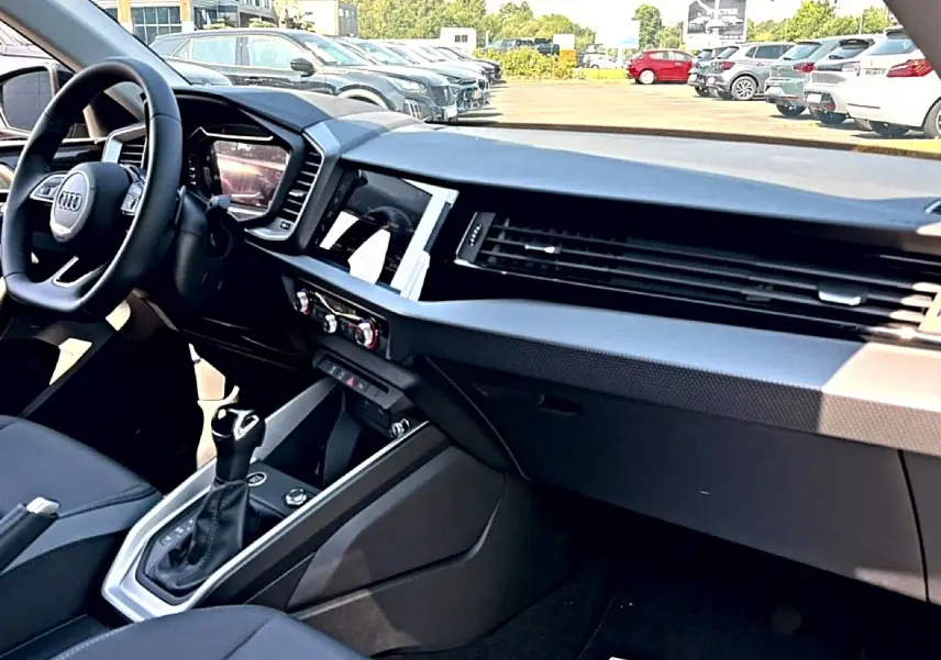 Intérieur noir de l'Audi A1 Sportback 2026 vu côté passager, avec tableau de bord moderne et levier de boîte auto.