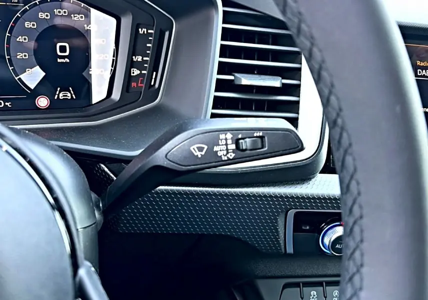 Vue rapprochée du tableau de bord noir de l'Audi A1 Sportback 2026, avec volant et commandes d'essuie-glace visibles.