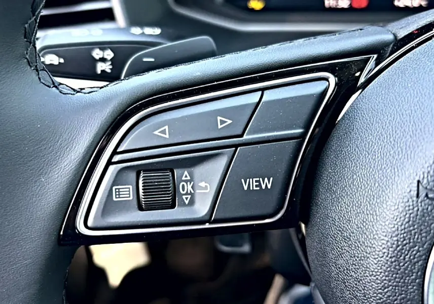 Gros plan sur les commandes gauche du volant cuir noir de l'Audi A1 Sportback 30 TFSI S line 2026.