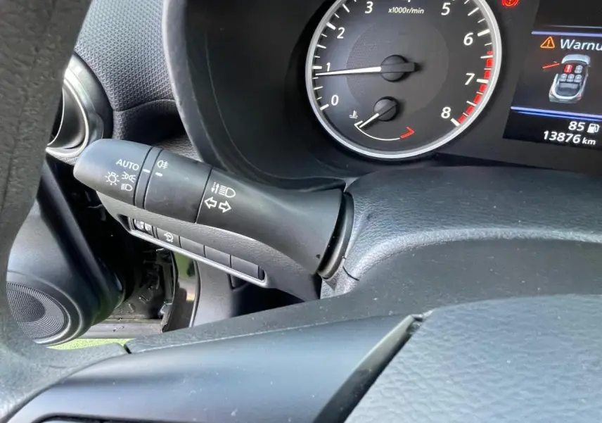 Gros plan sur le combiné d'instruments noir du Nissan Juke 2024 avec compte-tours et levier de clignotants à gauche.