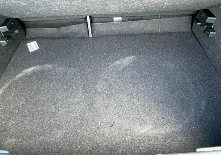 Vue rapprochée du coffre vide du Nissan Juke II 2024 en gris Ceramic, avec moquette grise et fixation arrière visible.