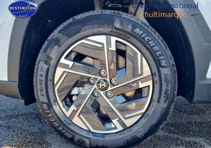 Gros plan sur la roue avant gauche du Hyundai Tucson blanc atlas avec jante alliage 17 pouces au design moderne.