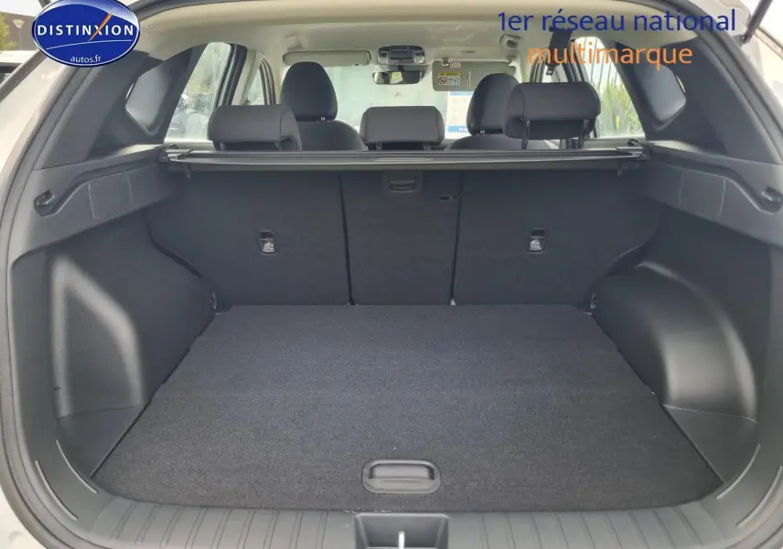 Coffre ouvert du Hyundai Tucson blanc atlas vu de l'arrière, montrant l'espace de chargement et la banquette arrière.