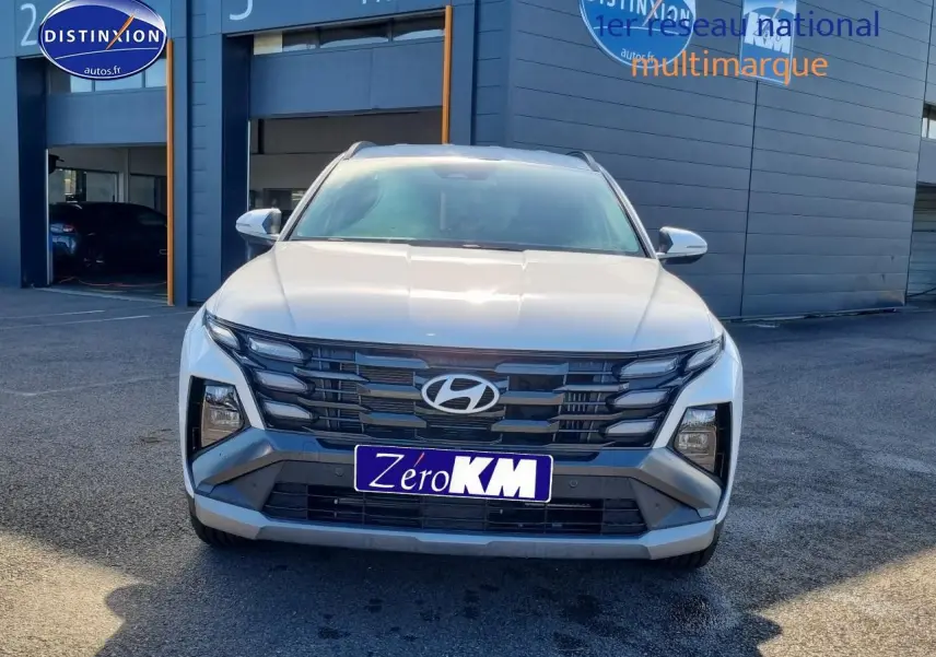 Vue frontale d'un Hyundai Tucson blanc atlas 2025 avec calandre grise et feux LED distinctifs.