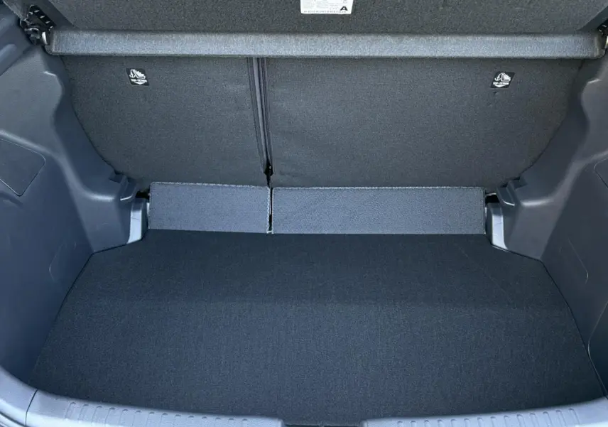 Coffre ouvert de la Toyota Yaris Hybride 2025 en noir intense, montrant l'espace de chargement intérieur vide.