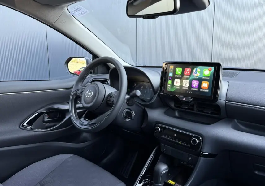 Intérieur de la Toyota Yaris Hybride 2025 vu côté conducteur, avec volant cuir et écran tactile multimédia visible.