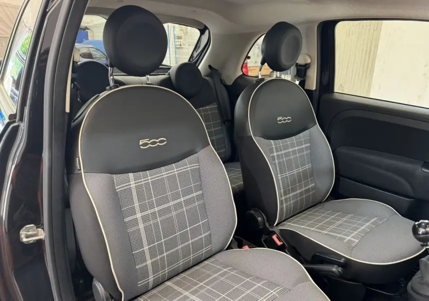 Vue intérieure côté droit montrant les sièges avant noirs avec logo 500 et motif à carreaux gris de la Fiat 500 Lounge 2019.
