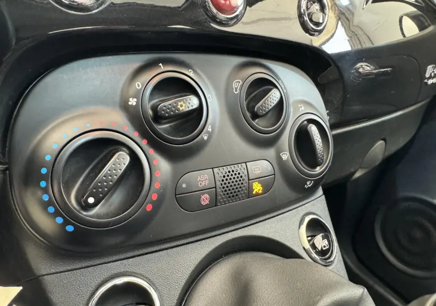 Gros plan sur les commandes de climatisation et tableau de bord noir de la Fiat 500 Lounge 2019.