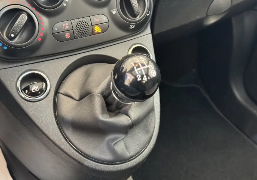 Le levier de vitesses manuel noir de la FIAT 500 1.2 8V 69ch Lounge vu en gros plan dans l'habitacle.