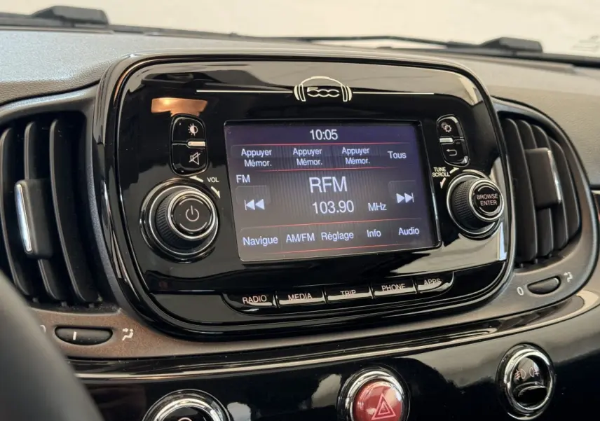 Vue rapprochée du tableau de bord noir de la Fiat 500 Lounge 2019, avec écran tactile affichant la radio FM RFM 103.90 MHz.