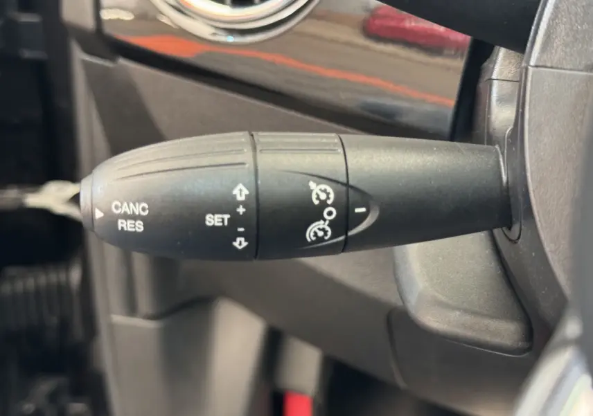 Gros plan sur la commande de régulateur de vitesse noire dans l'habitacle d'une Fiat 500 Lounge 2019.