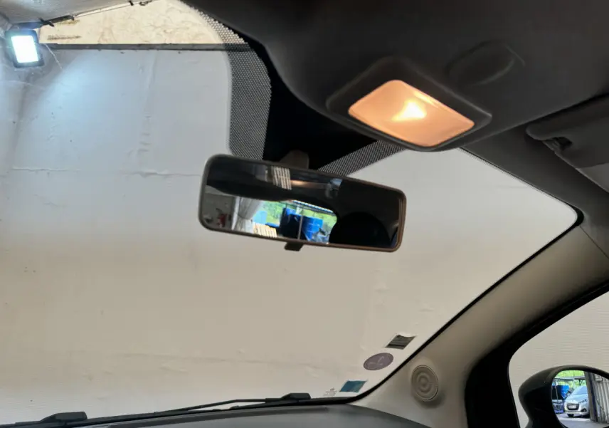 Vue intérieure avant de la Fiat 500 noire, montrant le rétroviseur central et la lumière de plafond allumée.