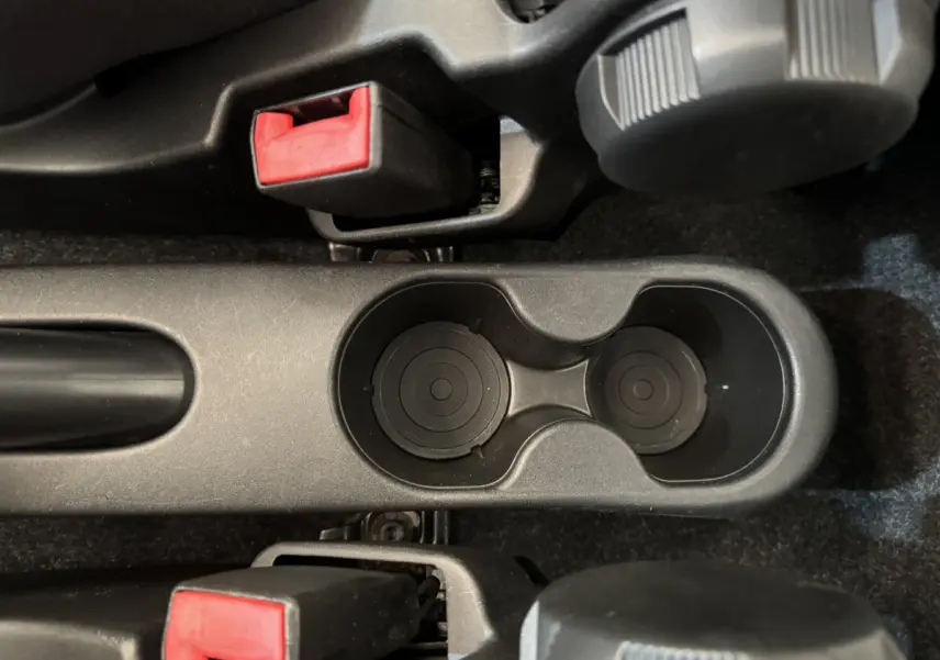 Gros plan sur les porte-gobelets noirs et les leviers de frein à main avec boutons rouges dans une Fiat 500 Lounge noire de 2019.