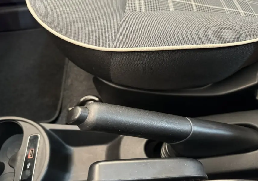 Gros plan sur le frein à main et la console centrale noire avec siège avant gris à motif à carreaux de la Fiat 500 Lounge 2019.