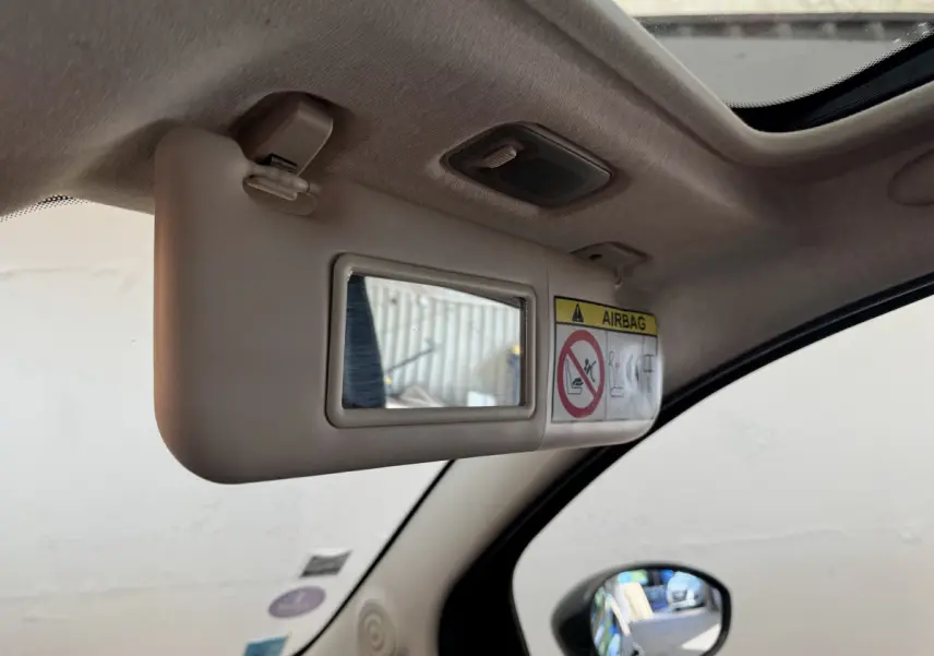 Détail du pare-soleil côté conducteur beige avec miroir et avertissement airbag dans un Fiat 500 noir 2019.