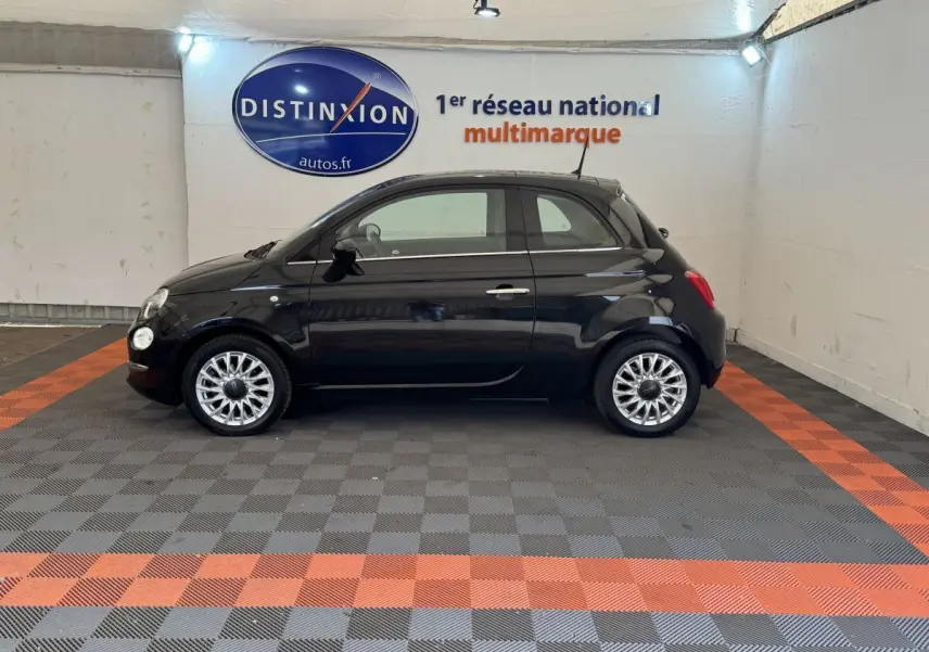 Profil côté gauche d'une FIAT 500 noire 2019 stationnée en intérieur avec jantes argentées et rétroviseurs noirs.