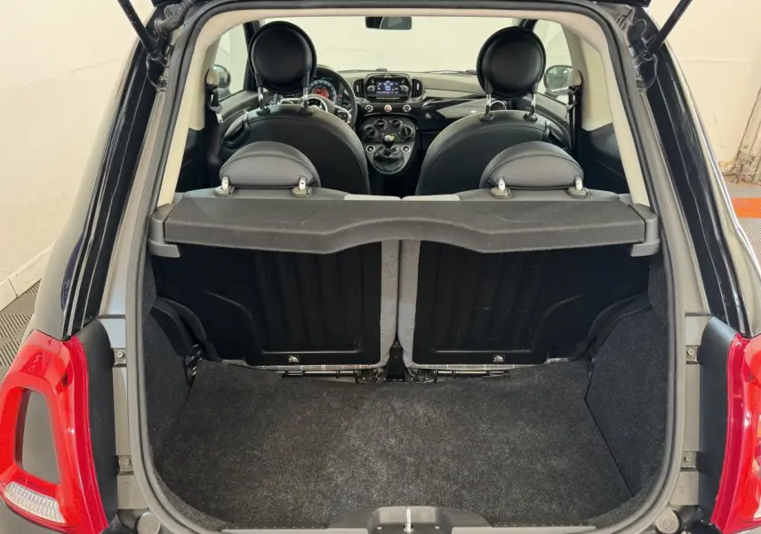 Vue arrière du coffre ouvert d'une FIAT 500 noire montrant l'intérieur et les sièges avant en cuir noir.