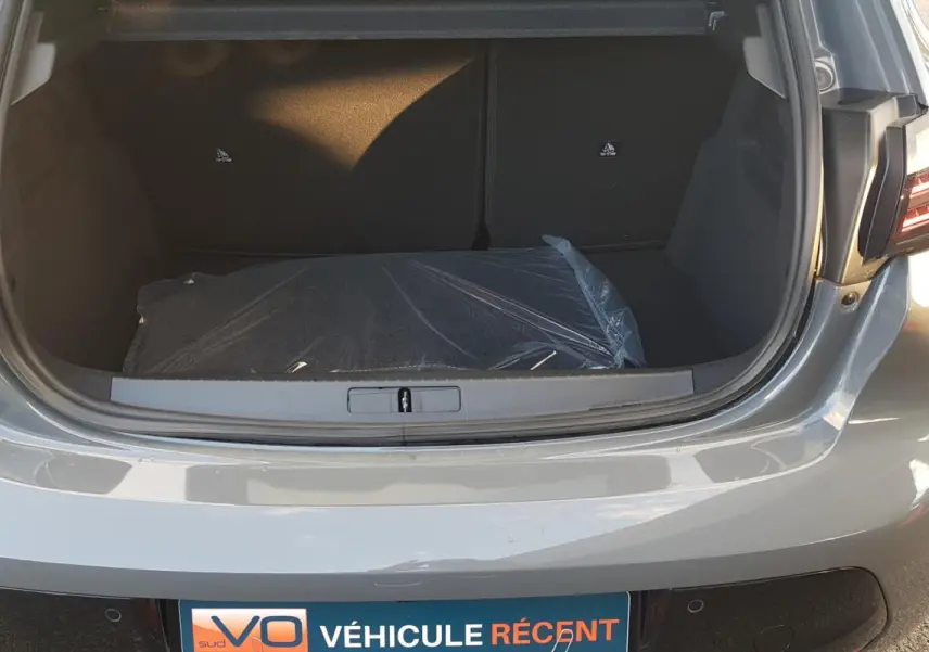 Coffre ouvert d’une Peugeot 208 gris 2025, vue arrière mettant en valeur l’espace de chargement et les feux arrière.
