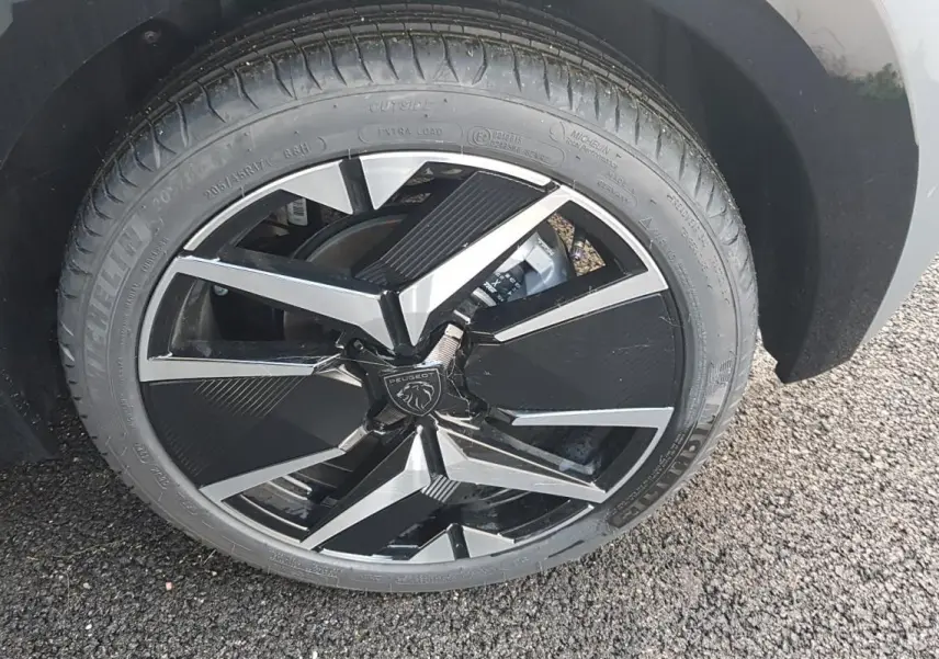 Gros plan sur la jante alliage 17 pouces noire et argentée du côté arrière droit d’une Peugeot 208 gris 2025.