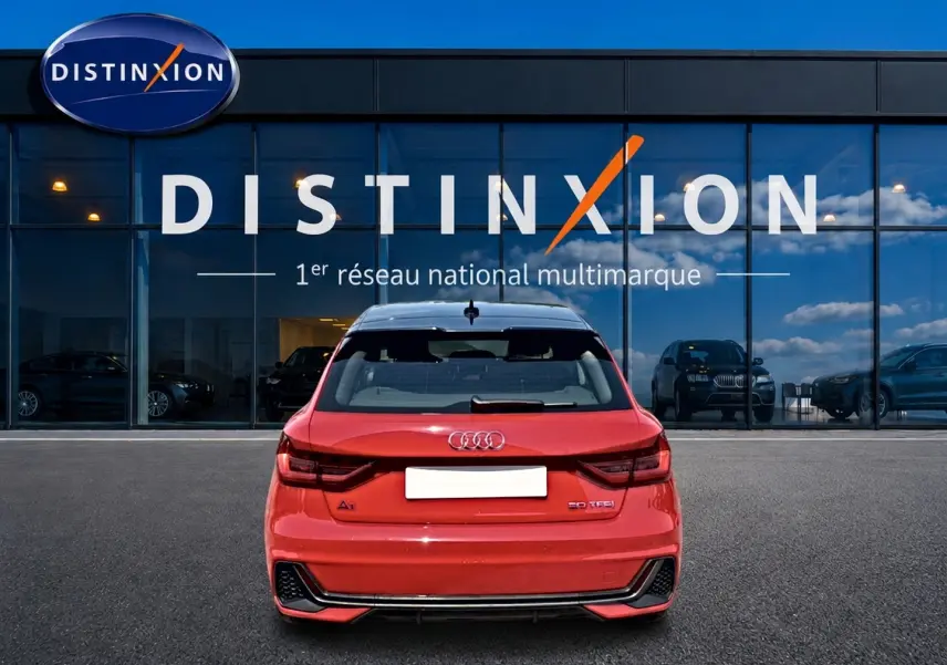 Vue arrière d'une Audi A1 Sportback 30 TFSI rouge et toit noir, avec becquet et feux arrière LED visibles.