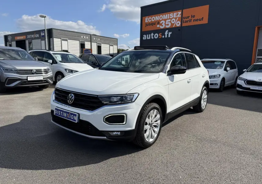 Volkswagen T-Roc blanc en 3/4 avant droit, avec toit ouvrant et jantes alliage visibles, sur parking extérieur.