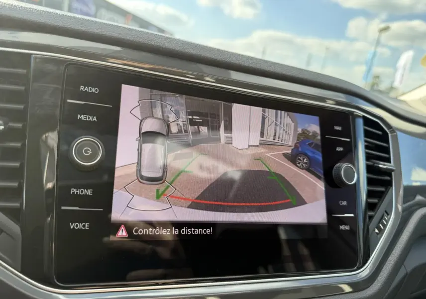 Écran central affichant la caméra de recul du Volkswagen T-Roc 2.0 TDI blanc, vue arrière avec guidage de trajectoire.