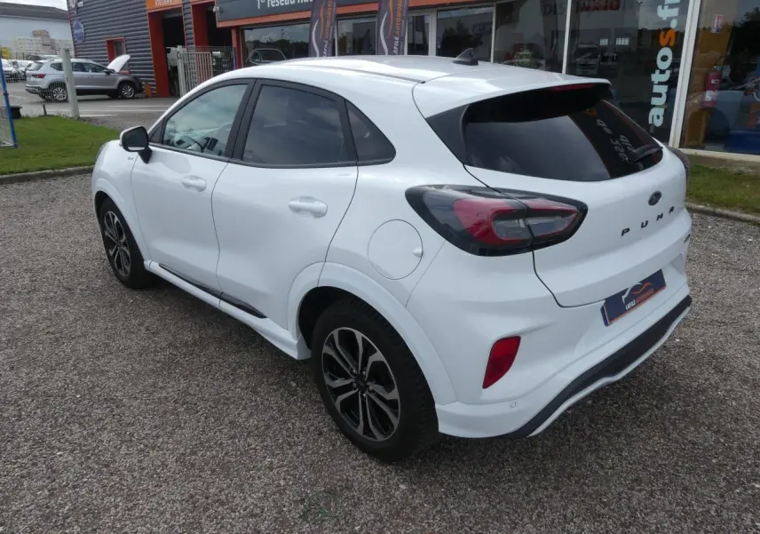 Vue 3/4 arrière droite du Ford Puma blanc ST Line avec vitres arrière surteintées et jantes alliage noires.