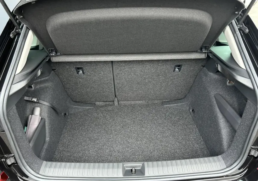 Coffre ouvert vu de l'arrière d'un Skoda Kamiq noir Magic, intérieur de coffre propre et spacieux.