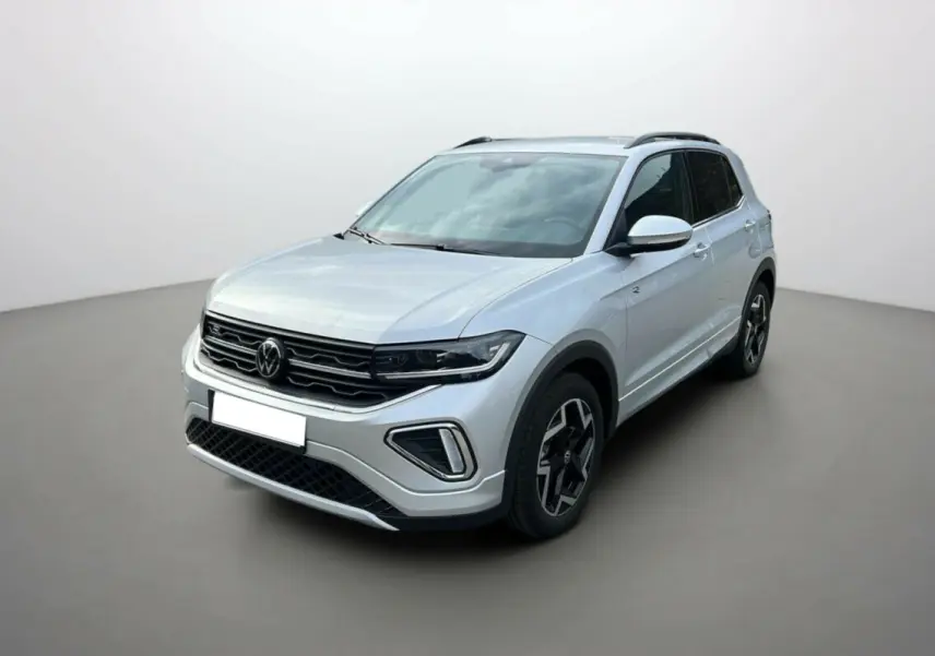 Volkswagen T-Cross gris argent en vue 3/4 avant droit, avec jantes alu 18 pouces et barres de toit noires.