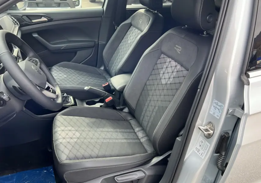 Intérieur avant droit du Volkswagen T-Cross gris argent, sièges tissu avec surpiqûres et logo R sur appuie-tête.