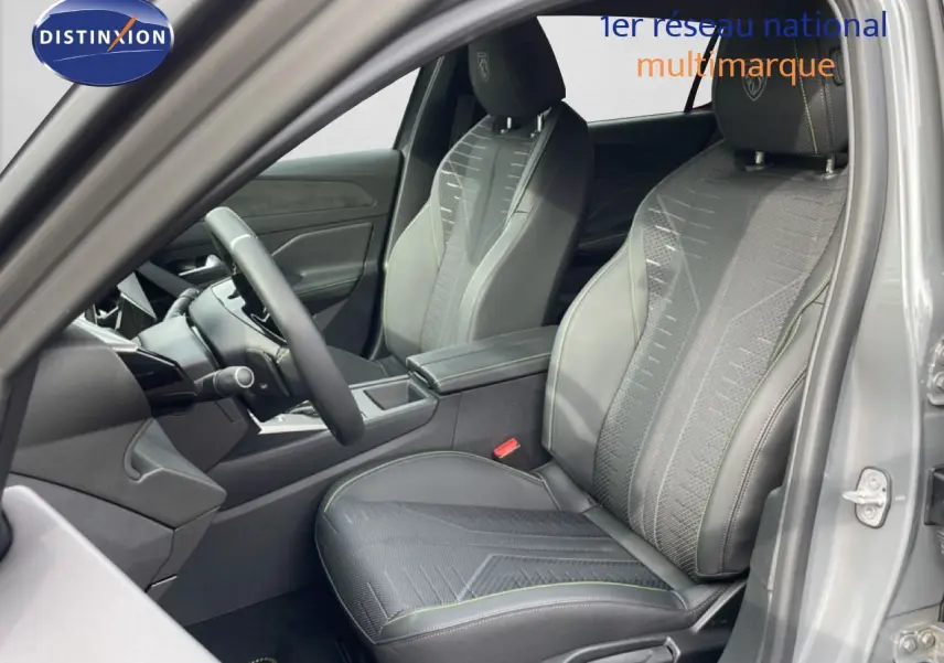 Vue intérieure côté conducteur de la Peugeot 308 gris selenium, mettant en valeur les sièges en tissu et cuir avec surpiqûres vertes.