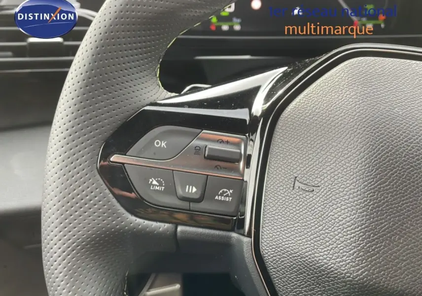 Gros plan sur le volant perforé gris avec commandes multifonctions du Peugeot 308 gris selenium metal, version hybride 2026.