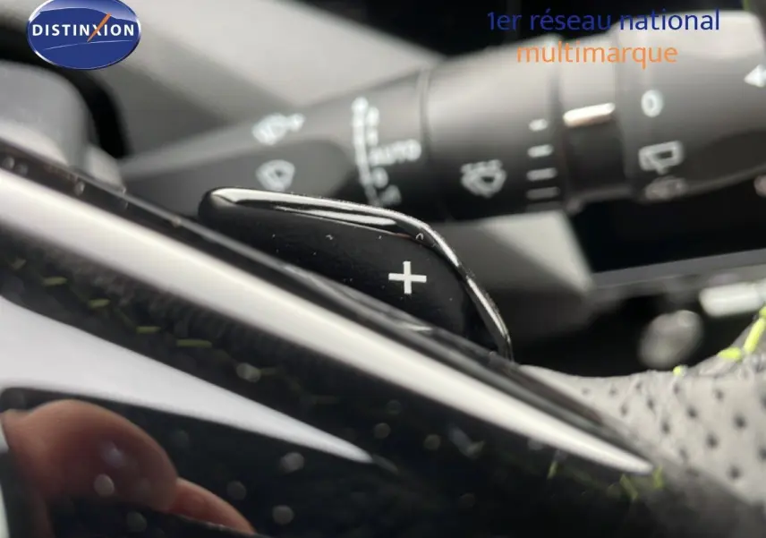 Gros plan sur la palette de changement de vitesse "+" en cuir noir perforé dans l'habitacle d'une Peugeot 308 hybride.