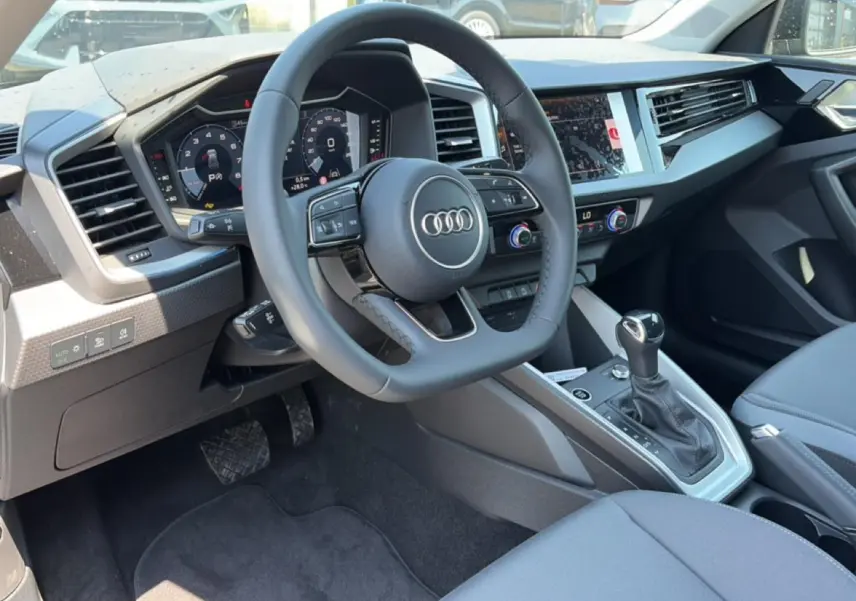 Vue intérieure côté conducteur de l'Audi A1 Sportback 30 TFSI 116 S line 2026, volant cuir multifonction et tableau de bord digital.