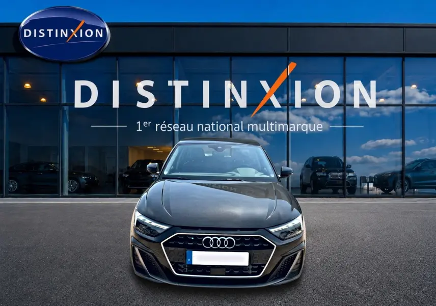 Audi A1 Sportback noir vue de face, mettant en valeur sa calandre hexagonale et ses phares LED devant un showroom Distinxion.