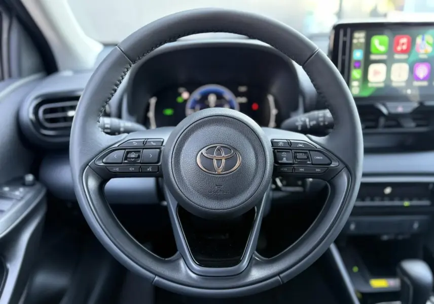 Vue centrée sur le volant cuir noir de la Toyota Yaris 2025 hybride avec tableau de bord numérique et écran tactile connecté.