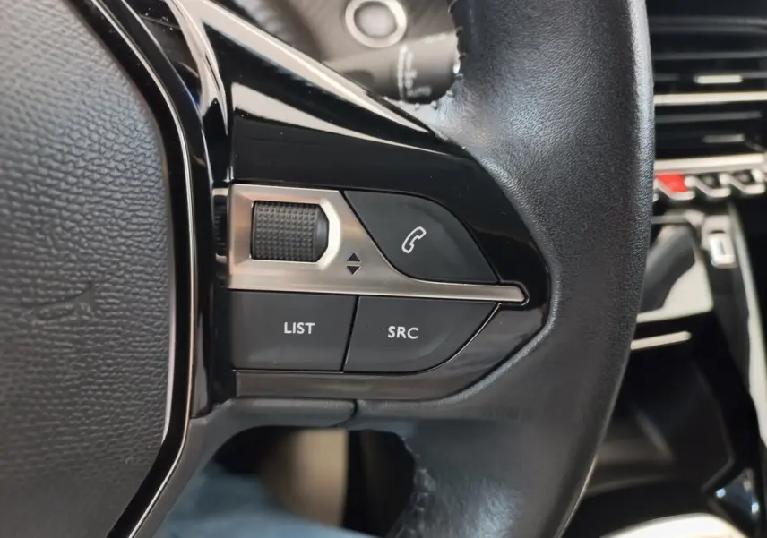 Gros plan sur les commandes gauche du volant cuir noir du Peugeot 208 PureTech 100 S&S Allure 2021.