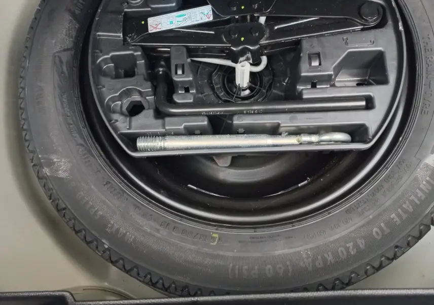 Gros plan sur la roue de secours et les outils de bord du coffre d'une Peugeot 208 blanche 2021.