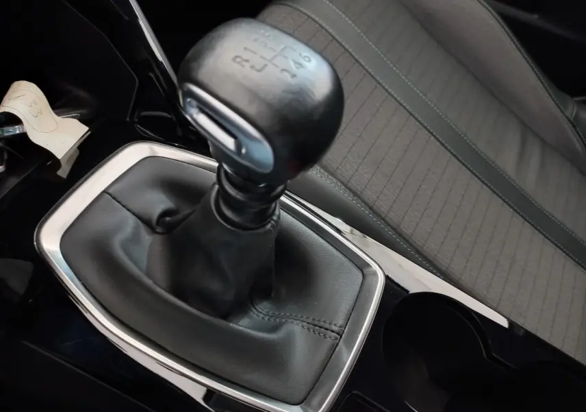 Gros plan sur le levier de vitesses manuel noir et la sellerie grise à motifs de la Peugeot 208 PureTech 100 S&S Allure 2021.