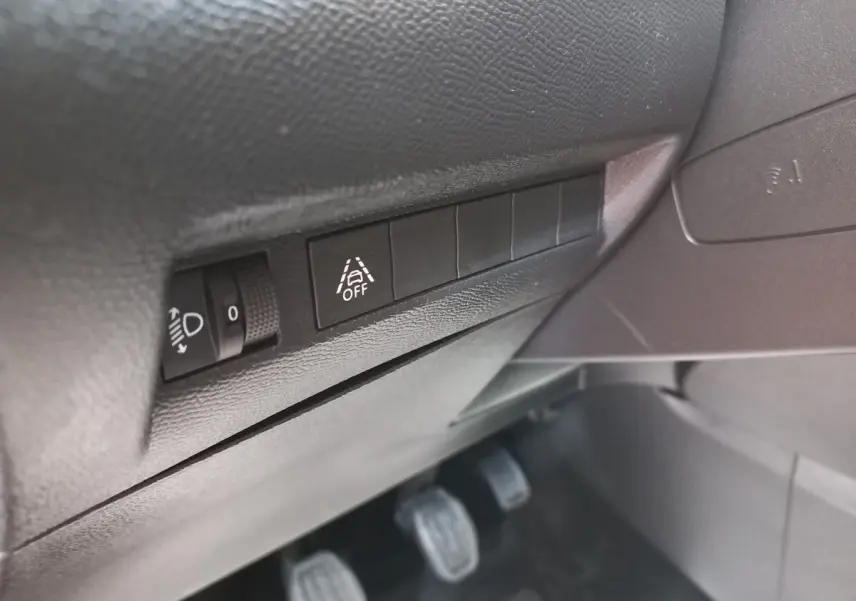 Détail des commandes côté gauche sous le tableau de bord de la Peugeot 208 blanche PureTech 100 S&S Allure 2021.