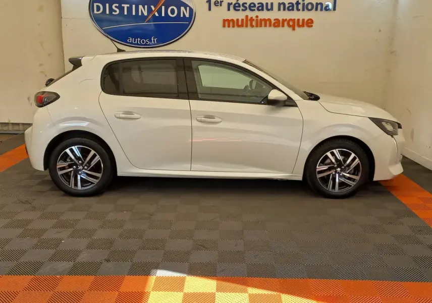 Profil côté gauche d'une Peugeot 208 blanche PureTech 100 S&S Allure 2021, avec jantes alliage et vitres teintées.
