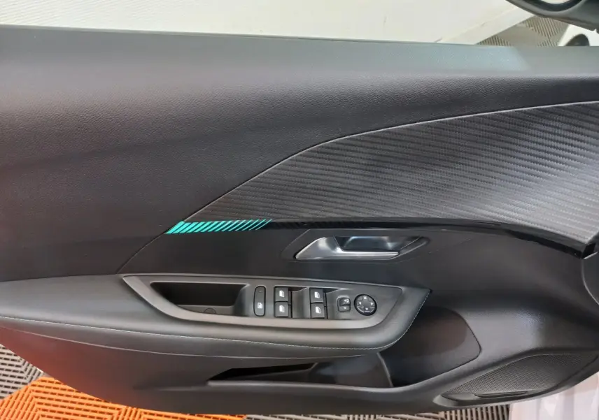 Vue rapprochée de la porte côté gauche d'une Peugeot 208 blanche, avec commandes de vitres et poignée argentée.